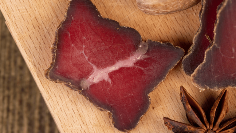Close-up of dried meat slices and star anise on a wooden board, illustrating the article on the nutritional benefits and safety tips regarding dehydrated dog food.